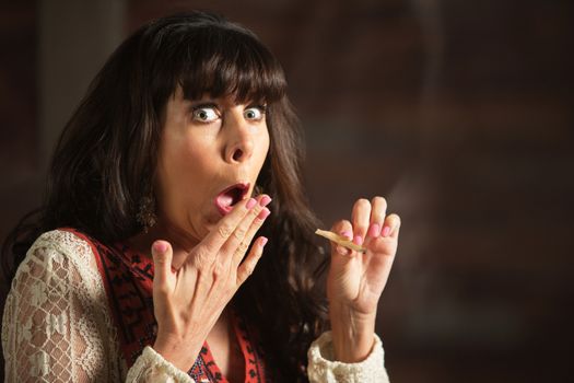 Embarrassed female smoker holding a marijuana cigarette while coughing