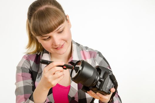 Photographer brush cleans the front of the lens on the camera