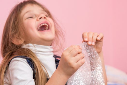 The girl laughs infectiously, playfield balls on the packaging bag