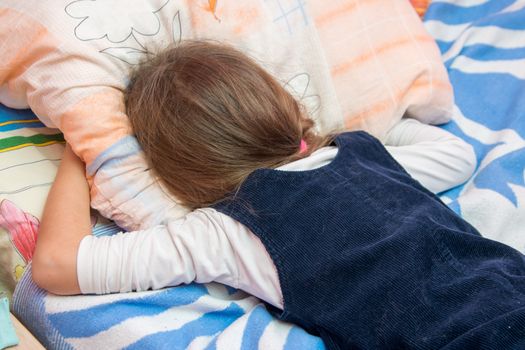 Upset little girl crying with his face buried in the pillow