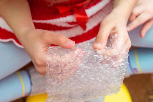 Top view of the child's hands pressing the bubbles on the packaging film