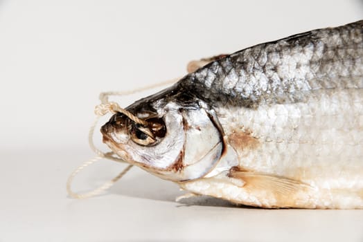 Dried fish on the table. Salty dry river fish on a wooden impressive background. Dead dry salty fish - snack to beer. Isolated on white. garland of salted and dried fish. dried fish hanging on a line, closeup. Dry fish on a wooden background. dried fish hanging on a rope, closeup.