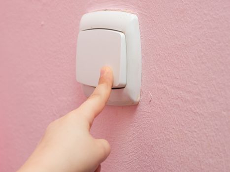 Child's hand finger presses the switch, close-up