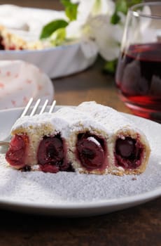 piece of cherry pie sprinkled with powder sugar on a plate