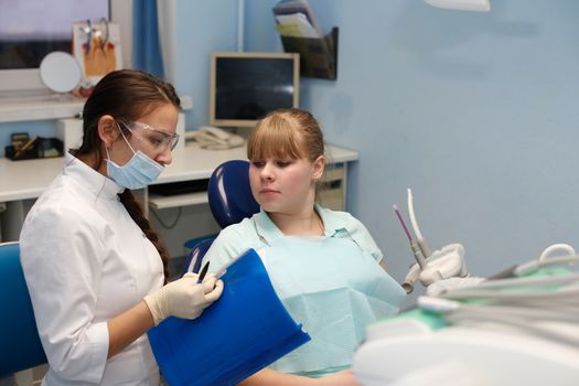 Dentist in a private office holds reception of the patient with pain. The Dentist Selects The Tool And Starts Examination Of The Teeth.