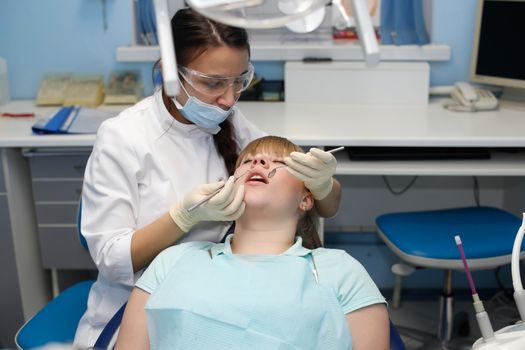 Dentist in a private office holds reception of the patient with pain. The Dentist Selects The Tool And Starts Examination Of The Teeth.