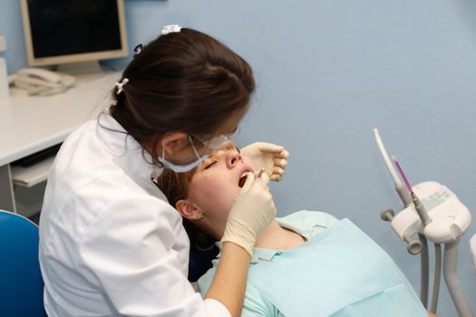 Dentist in a private office holds reception of the patient with pain. The Dentist Selects The Tool And Starts Examination Of The Teeth.