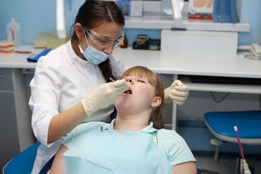 Dentist in a private office holds reception of the patient with pain. The Dentist Selects The Tool And Starts Examination Of The Teeth.