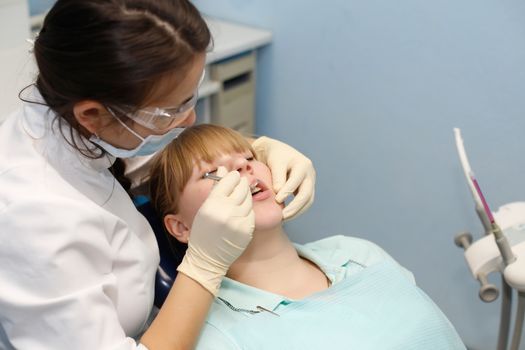 Dentist in a private office holds reception of the patient with pain. The Dentist Selects The Tool And Starts Examination Of The Teeth.