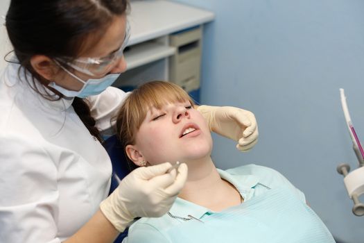 Dentist in a private office holds reception of the patient with pain. The Dentist Selects The Tool And Starts Examination Of The Teeth.