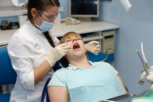 Dentist in a private office holds reception of the patient with pain. The Dentist Selects The Tool And Starts Examination Of The Teeth.