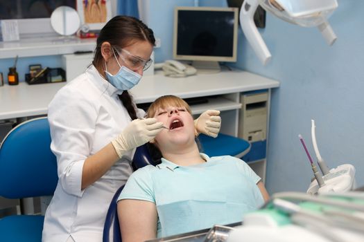 Dentist in a private office holds reception of the patient with pain. The Dentist Selects The Tool And Starts Examination Of The Teeth.