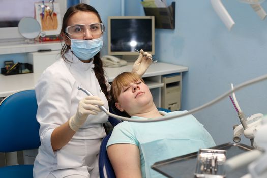 Dentist in a private office holds reception of the patient with pain. The Dentist Selects The Tool And Starts Examination Of The Teeth.