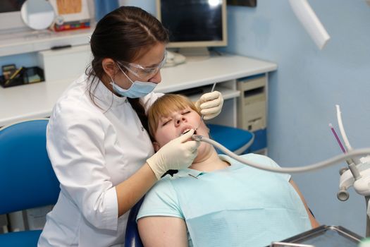 Dentist in a private office holds reception of the patient with pain. The Dentist Selects The Tool And Starts Examination Of The Teeth.