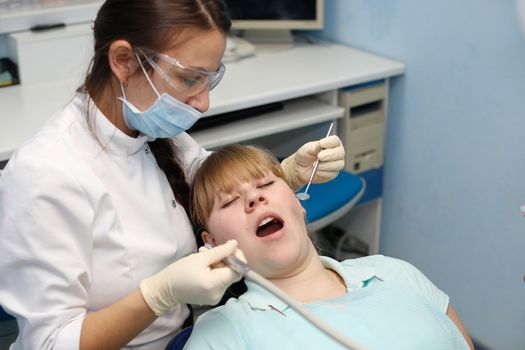 Dentist in a private office holds reception of the patient with pain. The Dentist Selects The Tool And Starts Examination Of The Teeth.