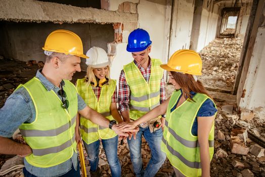 Four construction architects in building damaged in the disaster with folded hands, motivating for new business wins.