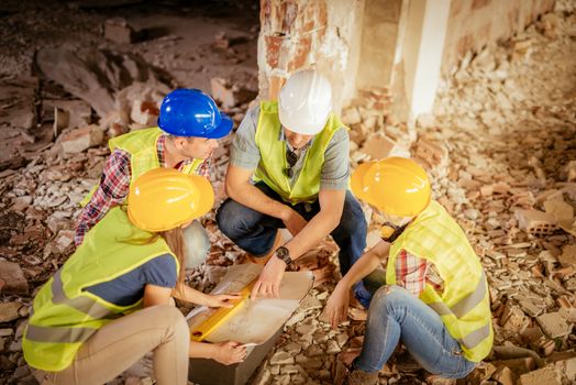 Four construction architects review plan in front building damaged in the disaster.