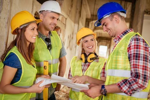 Four construction architects review plan in building damaged in the disaster.