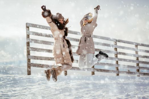 Two beautiful happy female friends enjoying and having fun while its snowing.