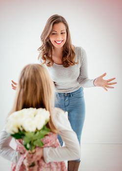 Cute daughter giving her mother Bouquet white roses for Mother's Day. Selective focus. Focus on background, on mom.