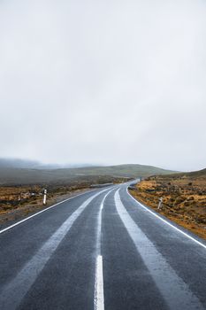 Road and mountains out in the Tasmanian country during winter on a rainy day.