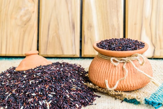 Hom Nil (black jasmine rice) in clay pot on sack wooden background