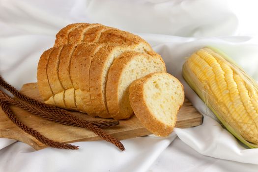 bread made from corn on the white fabric. Slices of corn bread laying on a chopping Board and Sweet corn cobs