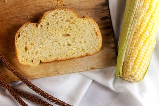 bread made from corn on the white fabric. Slices of corn bread laying on a chopping Board and Sweet corn cobs