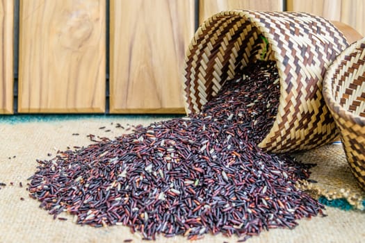 Hom Nil (black jasmine rice) in kratip on wood background