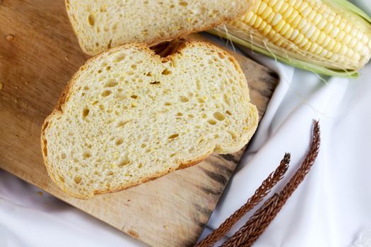 bread made from corn on the white fabric. Slices of corn bread laying on a chopping Board and Sweet corn cobs