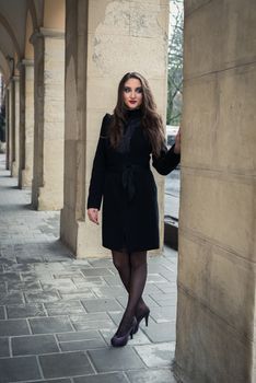 beautiful girl stands at the columns in the city