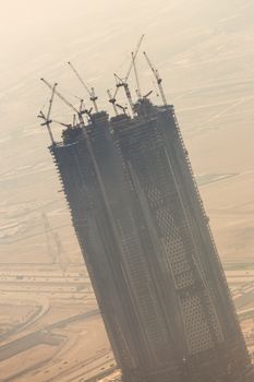 Huge skyscrappers construction site with cranes on top of buildings. Rapid urban and construction sector development or inflation of real estate bubble.