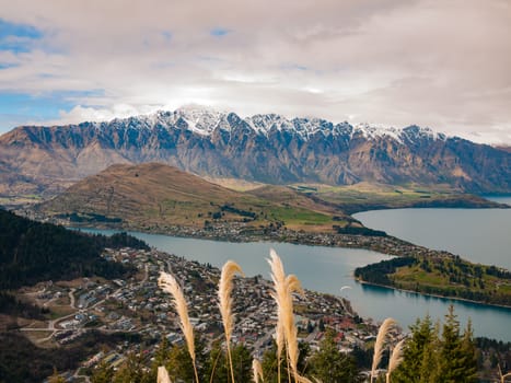 Cloudy sky snowy mountains and a town by a lake