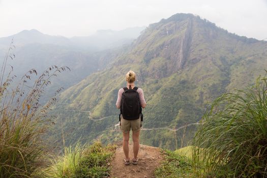 Woman enjoying pristine nature and beautiful view of tea plantations from the top of Small Adams peak near Ella, Sri Lanka. Tracking outdoors tourist adventure.