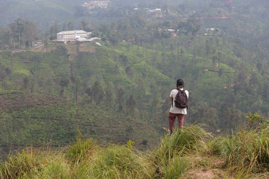 Traveler enjoying pristine nature and beautiful view of tea plantations from the top of Small Adams peak near Ella, Sri Lanka. Tracking outdoors tourist adventure.