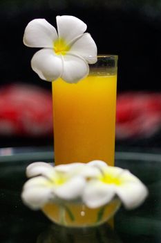 a freshly squeezed fresh orange juice, close-up with a Magnolia blossoms on the glas