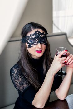 a beautiful girl sitting in the cafe with black mask and wine