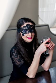 a beautiful girl sitting in the cafe with black mask and wine