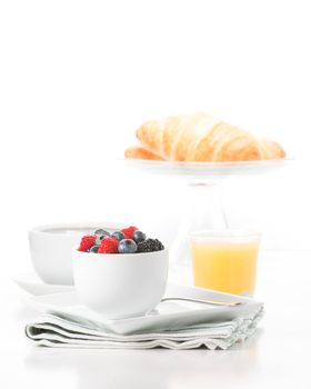 Small bowl of fresh berries served with croissant, coffee and orange juice.