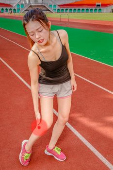 Asian woman jogger holding throbbing red painful leg on track