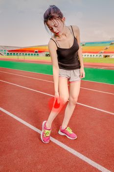 Asian woman jogger holding throbbing red painful leg on track