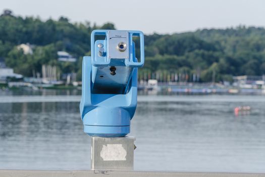 Stationary binoculars overlooking a lake at clear blue sky.