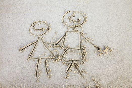 The child has drawn mum and daddy on sand