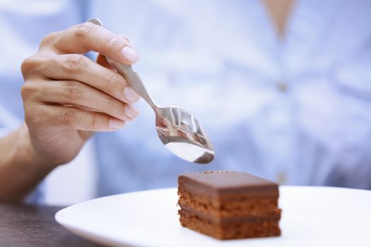 Hand of woman eating chocolate cake