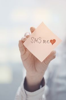 Woman holding sticky note with SMS me text
