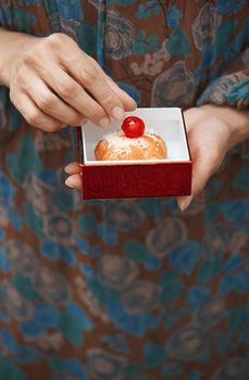 Woman holding eclair in the box. Vertical photo