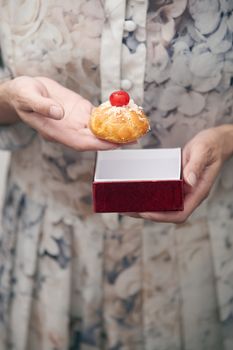 Woman holding eclair and red box. Vertical photo