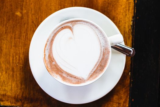 cup of hot latte art coffee on wooden table