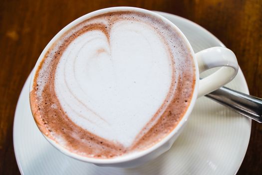 cup of hot latte art coffee on wooden table