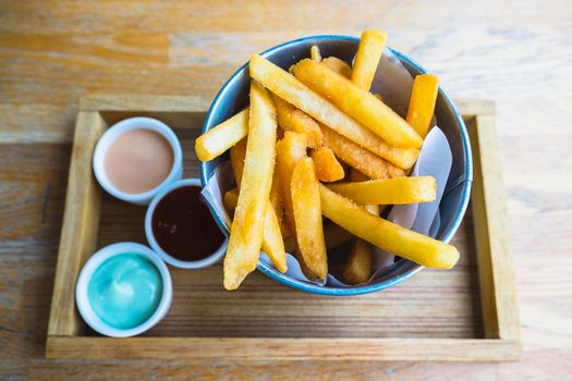 french fries in bucket with ketchup on wooden tray